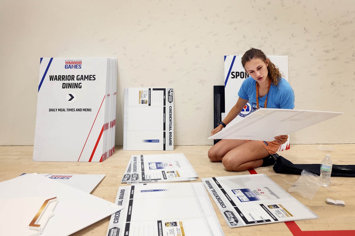 Gracie Huebner ’26, Communications Intern, organizes signage during the Dept. of Defense Warrior Games on campus. Photo by Jamie Cotten / Colorado College